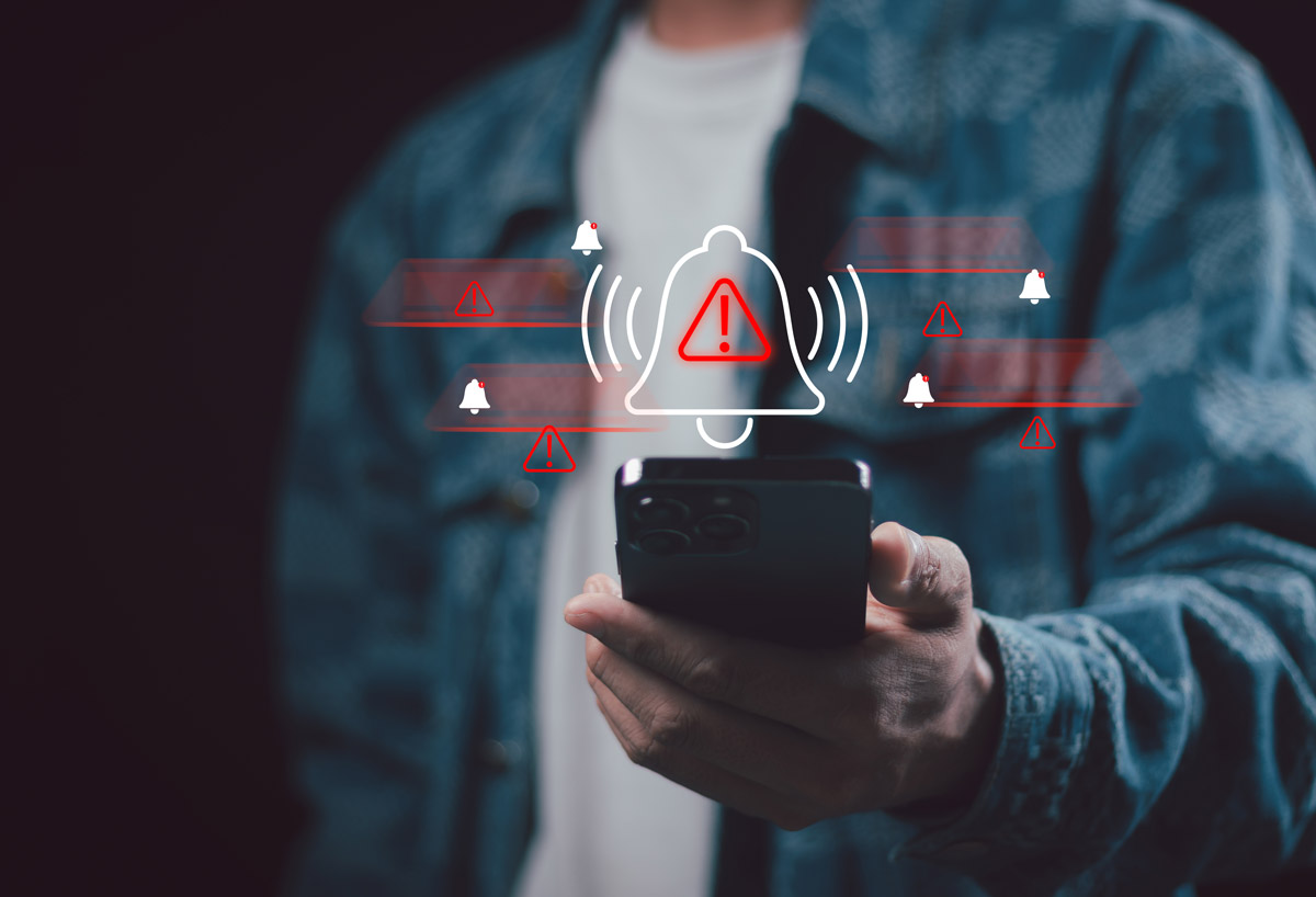An unseen person looks at their phone, with an illustration of an alert overlaid.